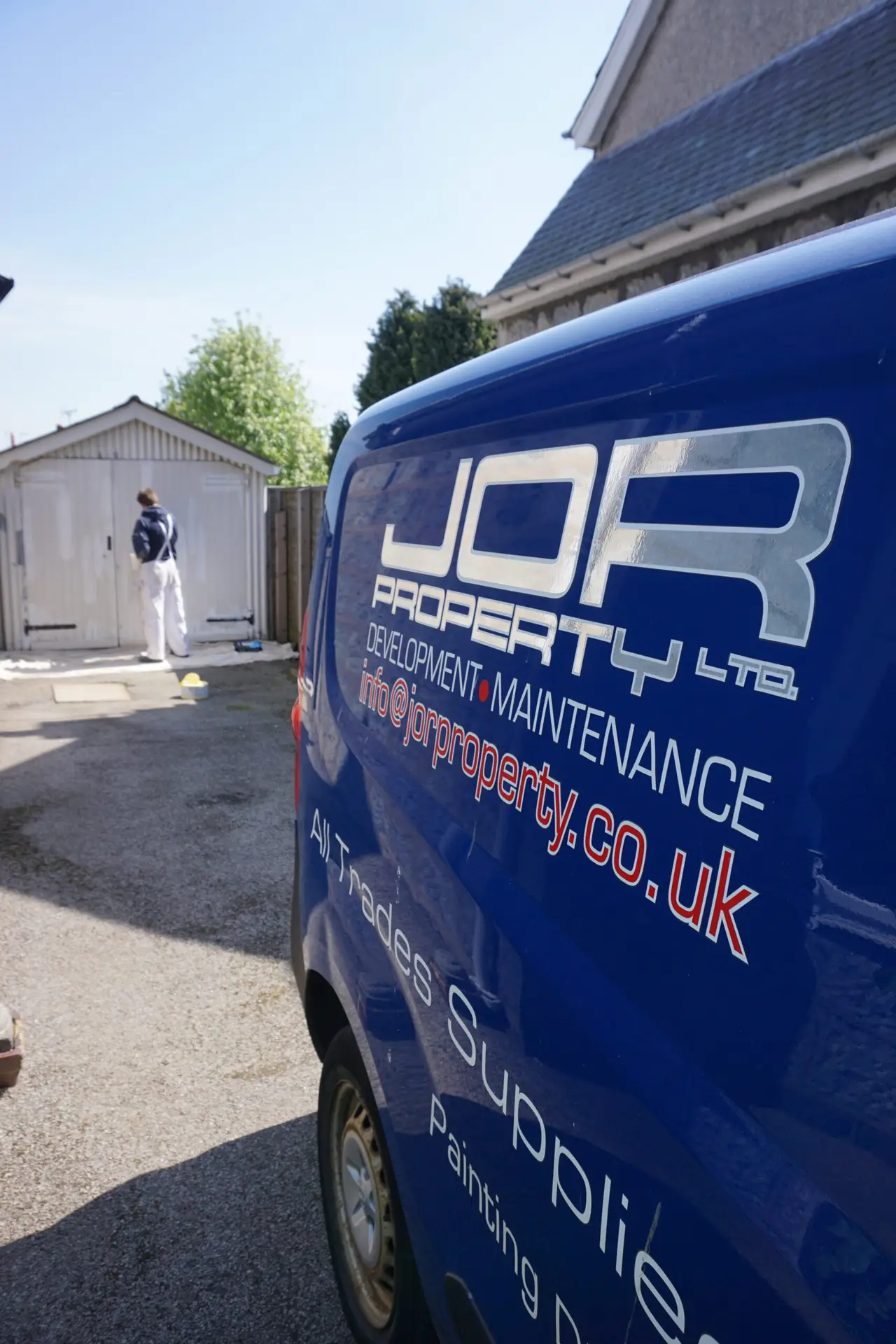 JOR Property van with a painting and decoration expert working on an exterior door to a garage